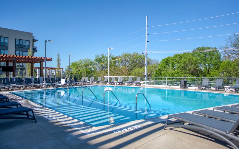 Zero-entry pool with poolside lounge chairs at Residences at Capitol View Apartments
