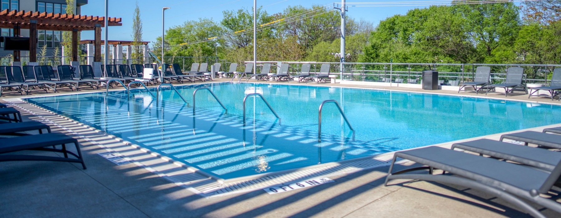 Zero-entry pool with poolside lounge chairs at Residences at Capitol View Apartments