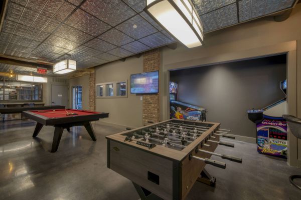 Residences at Capitol View Resident game room with pool table, foosball, and pinball machines